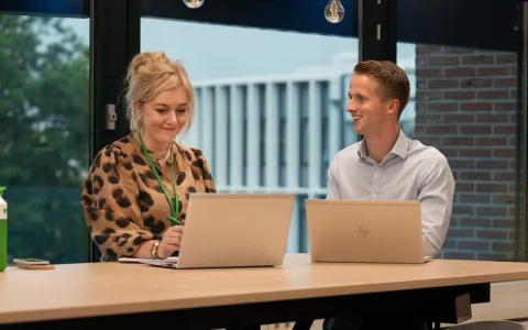 Zwei Mitarbeitende von TVM sitzen an einem Hochtisch.
